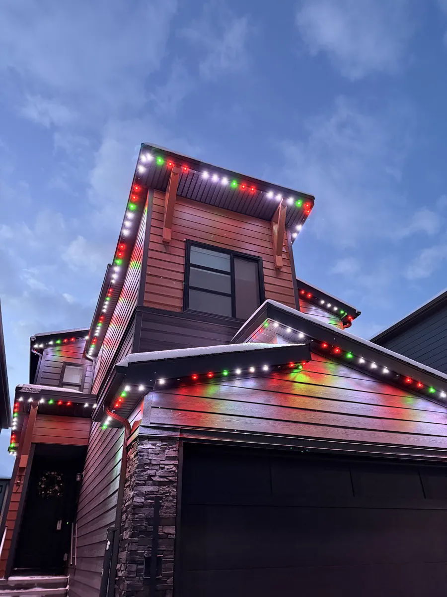 The same modern home lit red, green and white for the holidays