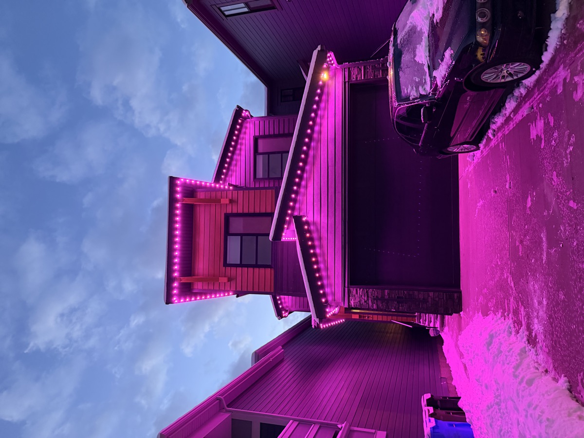 Teal and orange permanent event lighting on Calgary home at sunset