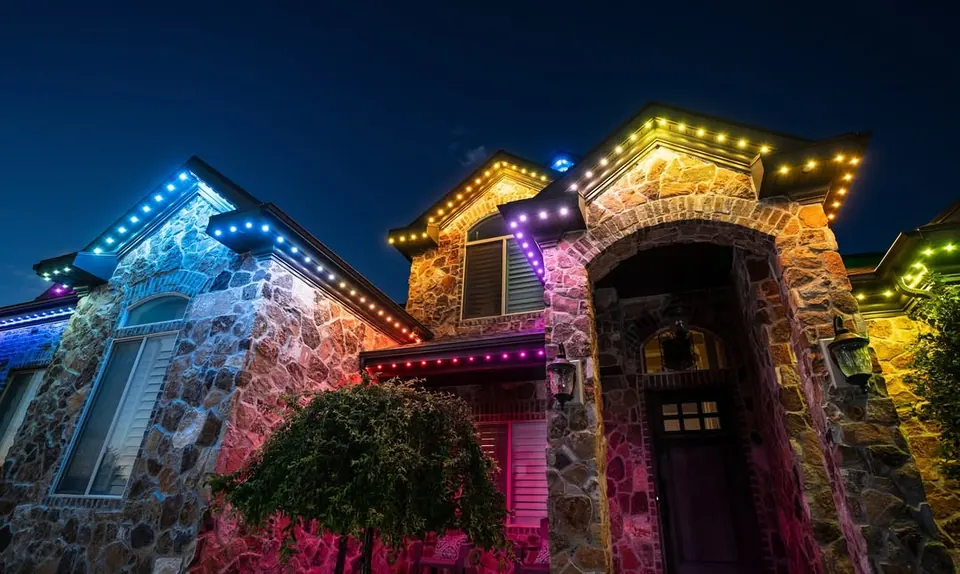Stone home at night with permanent lighting running a multi-colour pattern across its gables