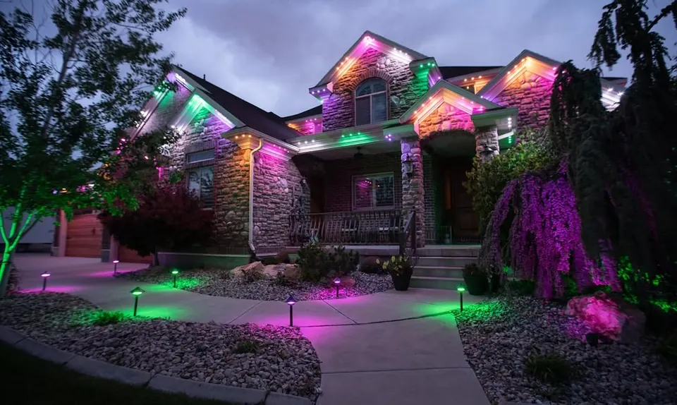 Landscaped front yard at dusk with multi-colour permanent roofline lighting and path lights