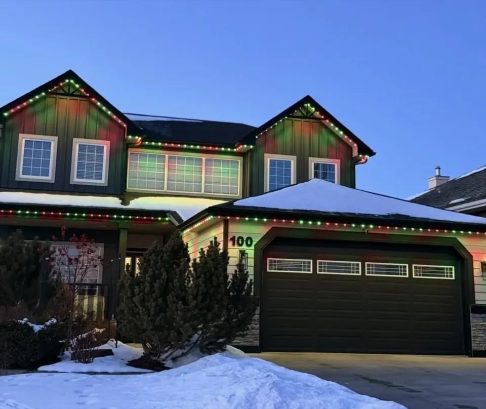Two-storey Calgary home with red, green and white permanent Christmas lighting in the snow