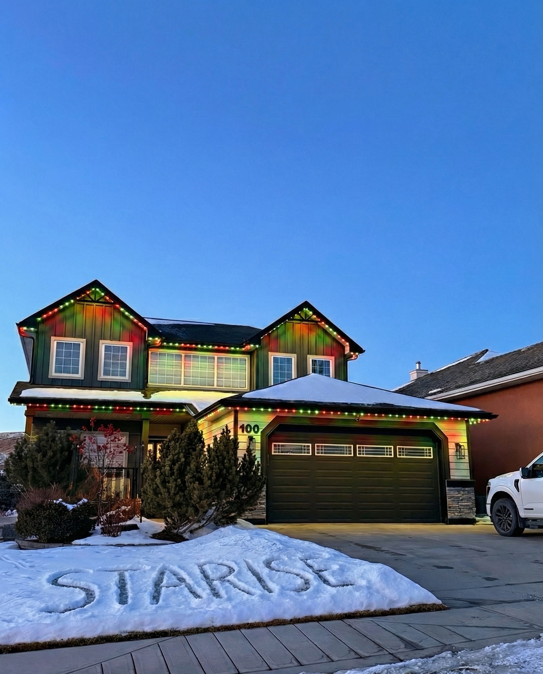Red and green permanent LED lights on a snowy Calgary two-storey home in winter