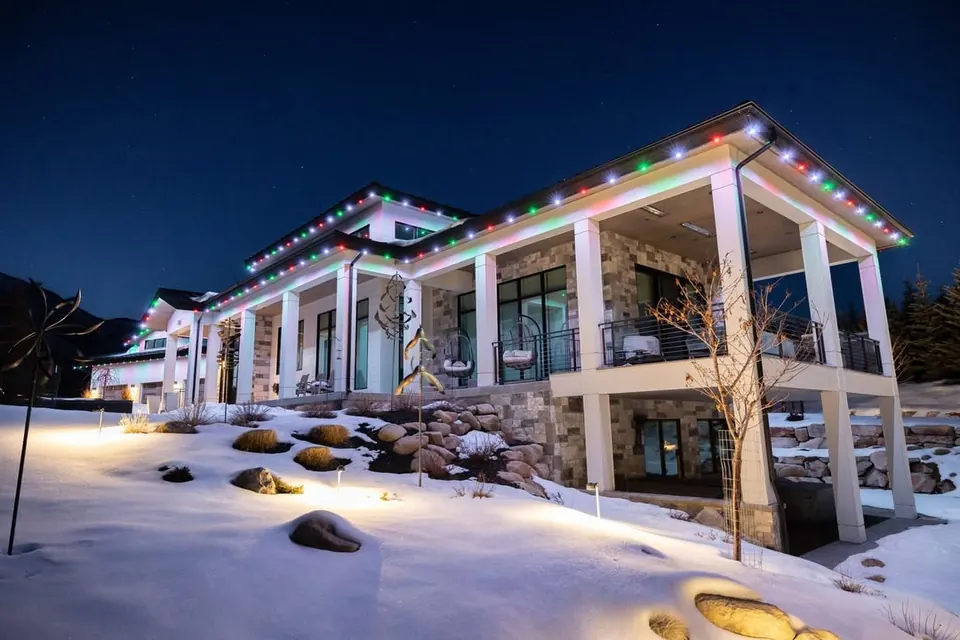 Snow-covered home with a pillared porch and multi-colour permanent Christmas lighting