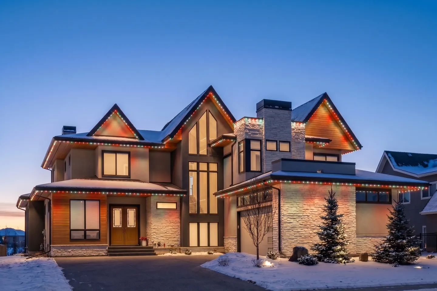 Modern Calgary home at blue hour lit red and white along every roofline