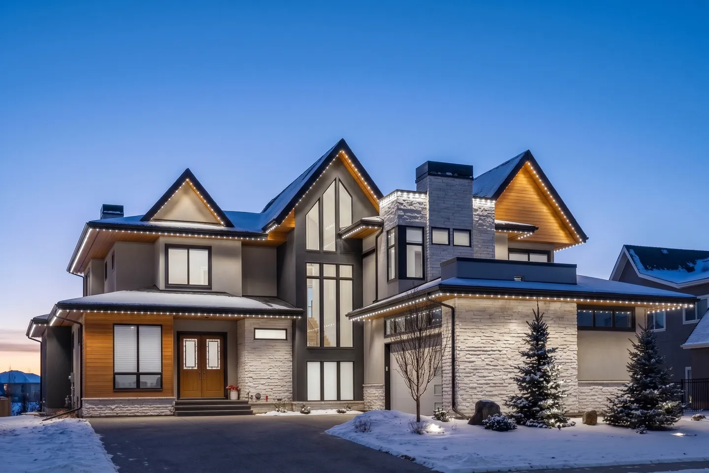 White permanent lighting illuminating a home's rooflines at dusk