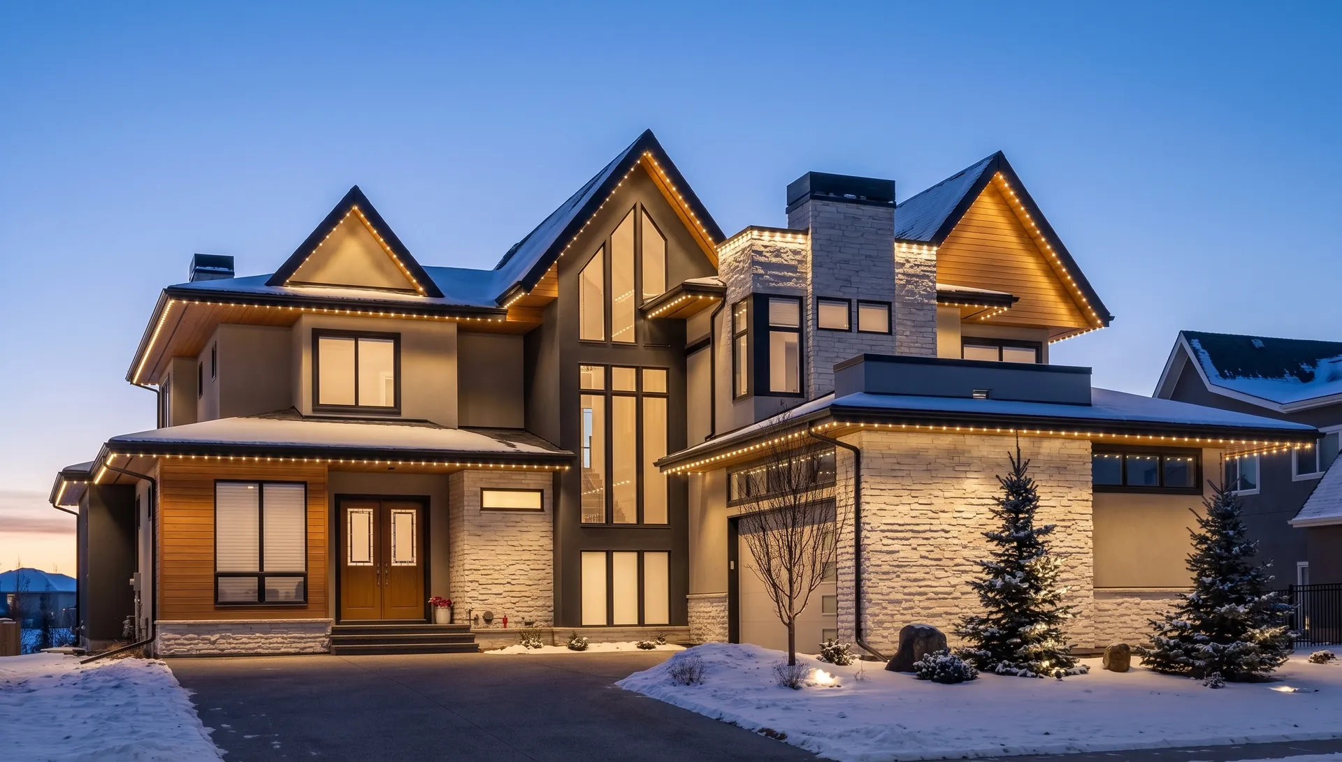Modern home at dusk in winter with warm white permanent lights along every roofline