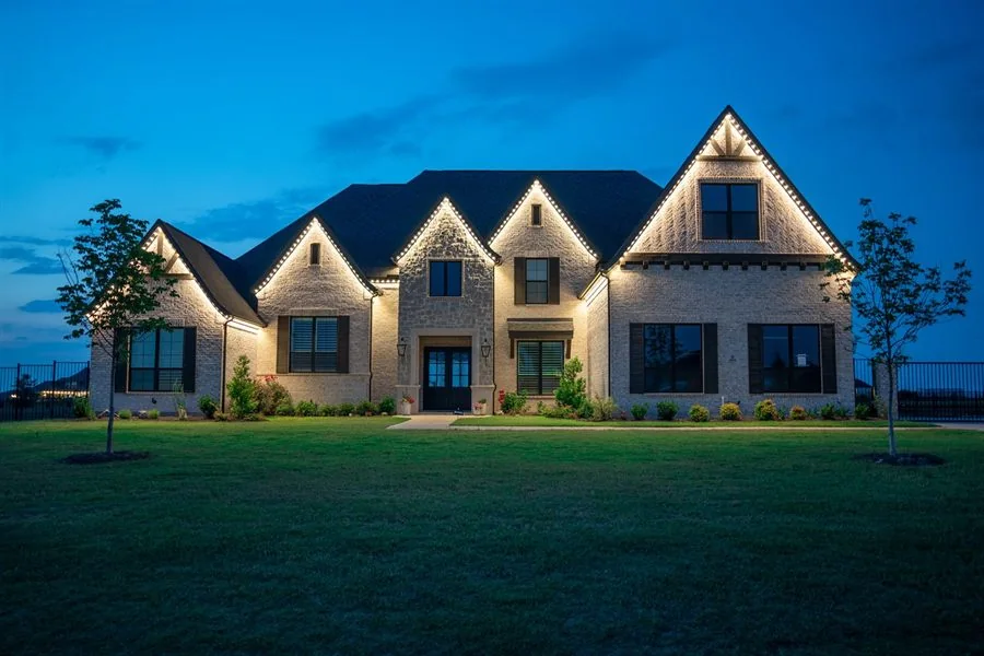 Brick home at blue hour with warm white permanent lighting along every gable